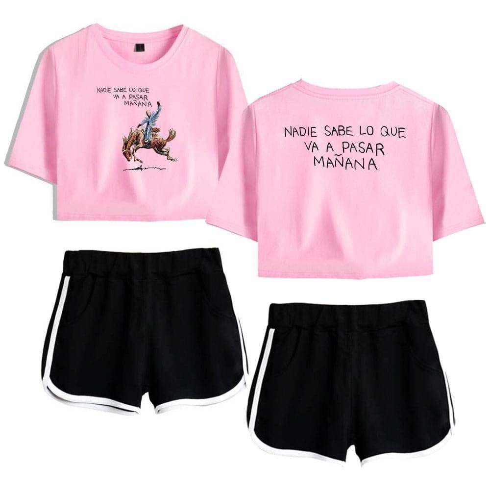 Pink crop top with a graphic of a person riding a horse and the phrase "NADIE SABE LO QUE VA A PASAR MAÑANA" in Spanish. Paired with black athletic shorts with white trim. Suitable for casual wear or athletic activities.