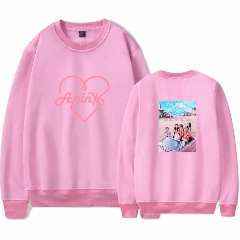 Pink sweatshirt featuring the girl group Apink with a heart-shaped logo and a vintage-style photo of the group on the back. Perfect for fans wanting stylish and cozy merch.