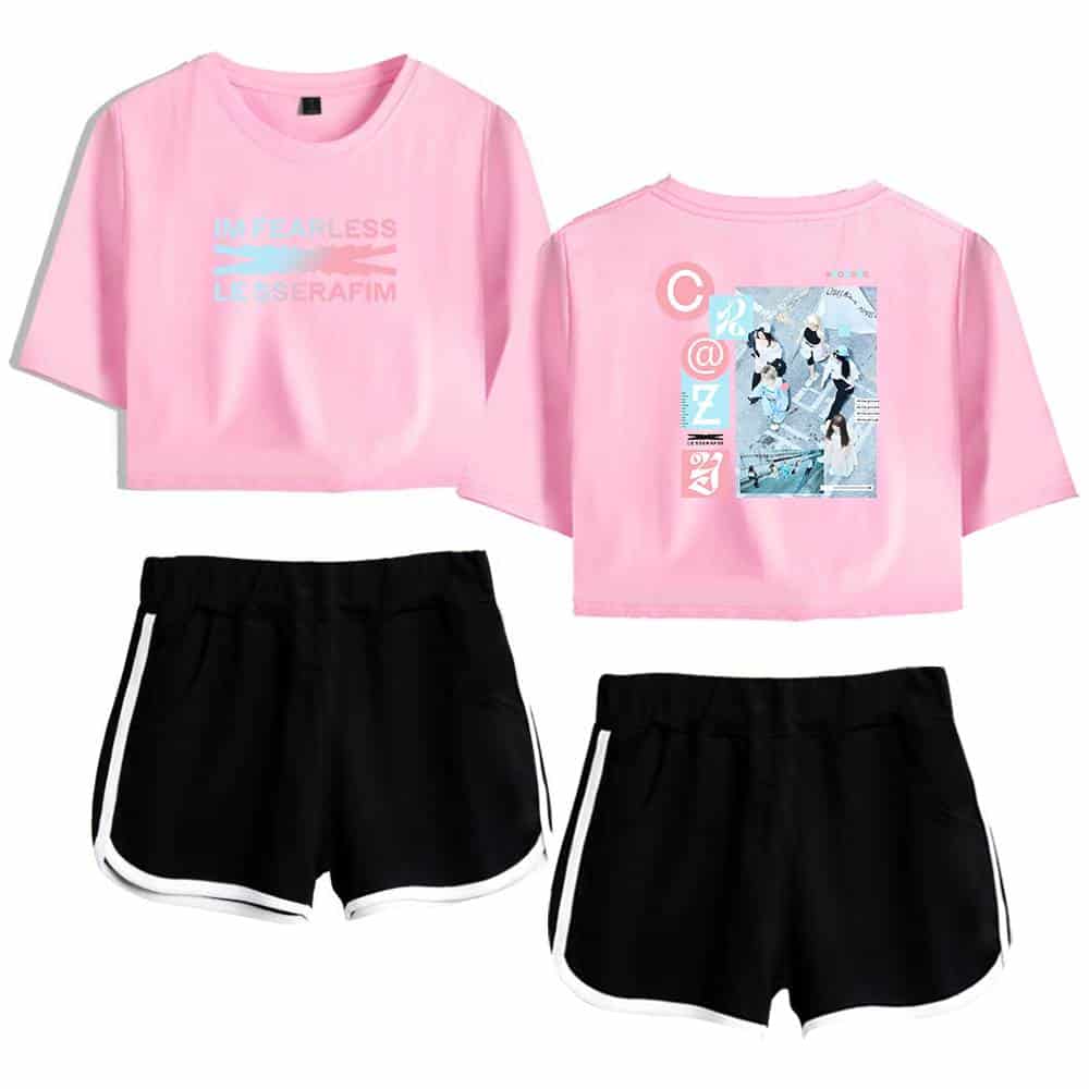 Pink graphic crop top with abstract text and image design, paired with black athletic shorts featuring white trim. Perfect casual streetwear for a trendy, sporty look.