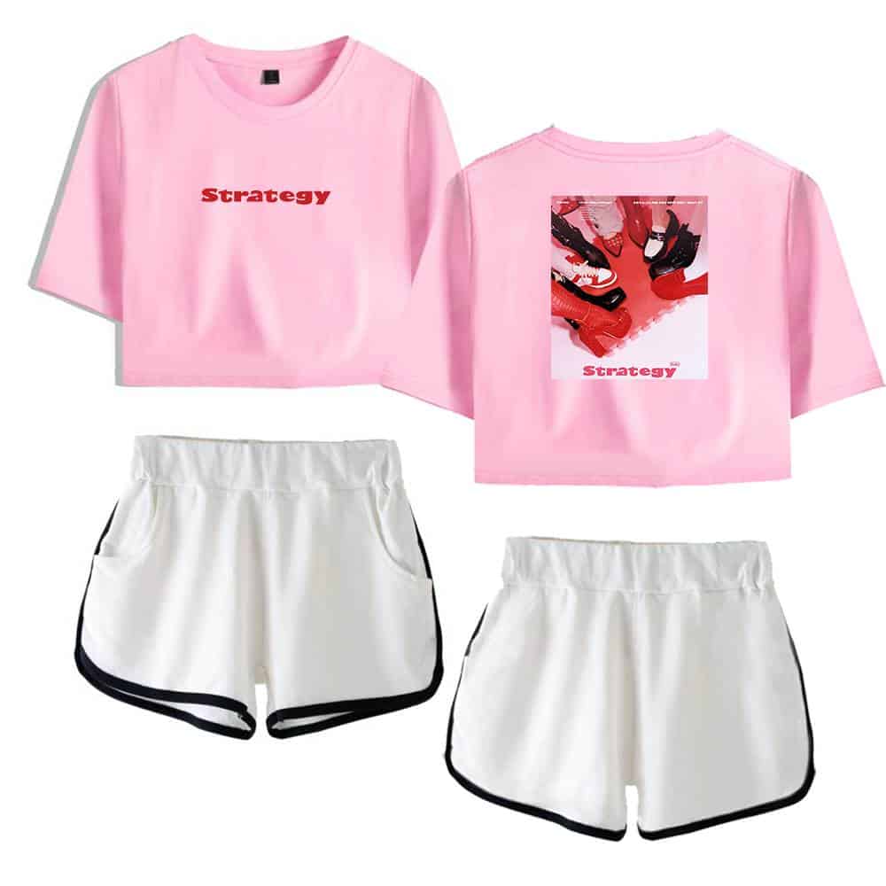 Pink cropped t-shirt with "Strategy" text and graphic print on the back, paired with white athletic shorts with black trim. Casual sporty look suitable for workouts or leisure.